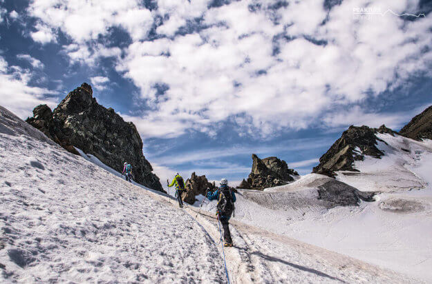 eine Seilschaft mit drei Personen auf einem Gletscher an der Wildspitze. Der Himmel ist bewölkt. Im Hintergrund sind kleine Gipfel zu sehen.